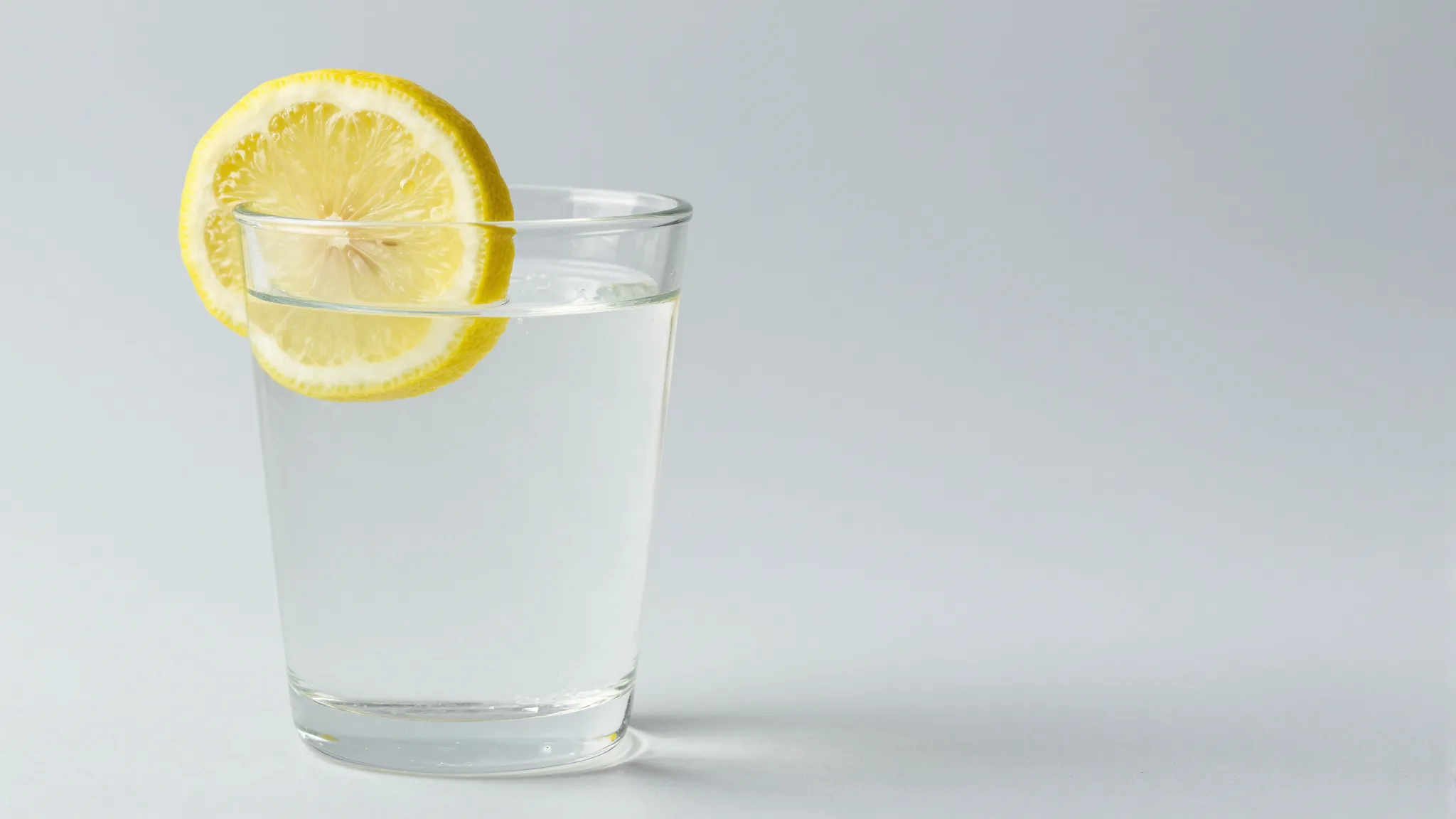 A glass of crystal clear water with lemon on a clean surface...