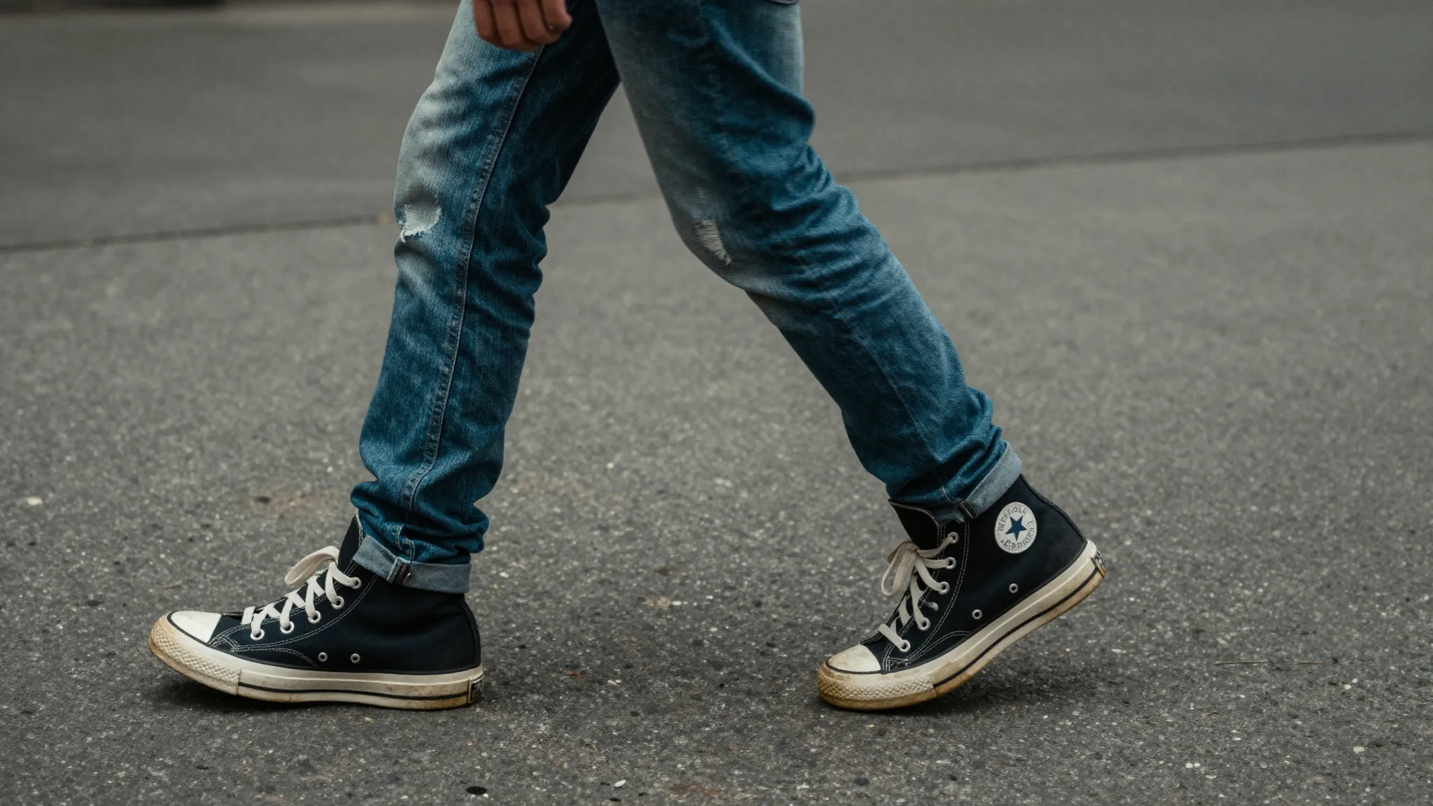 Lower body shot of a teenage boy in motion, walking on a gri...