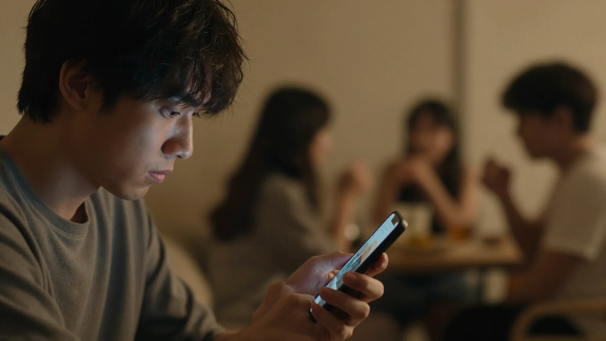 A person looking regretfully at a smartphone, warm room ligh...