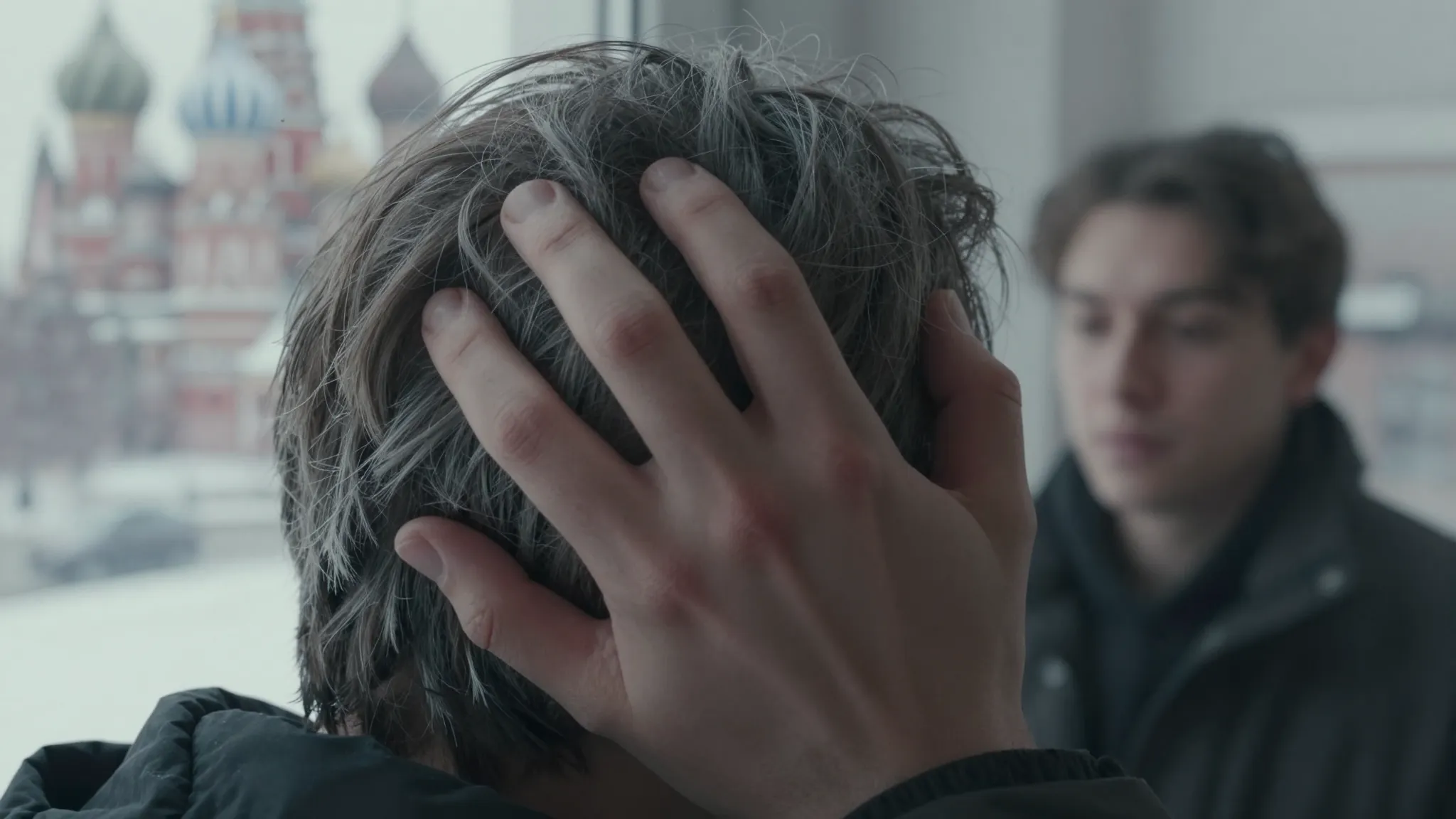 A close-up of a person's hand touching their graying hair, w...