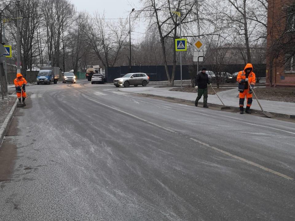 На Институтском переулке в Долгопрудном рабочие вручную убирают снег и смет с тротуаров