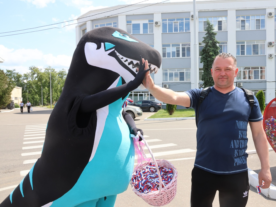 Динозавр раздает в Коломне ленточки с триколором