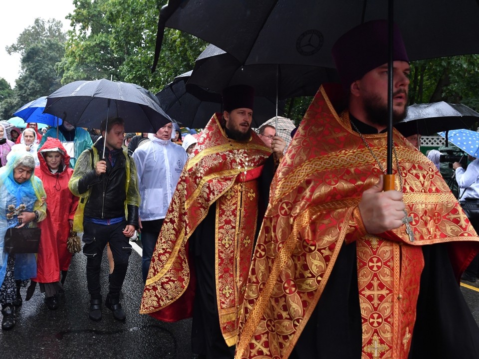 Участники пешего Крестного хода из Мытищ в лавру спасаются от ливня под зонтами