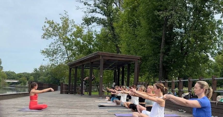 группа людей занимается йогой на набережной исторического города