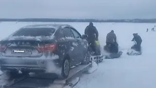 Смельчаки перевозят машины с помощью снегоходов через закрытую переправу на Печоре