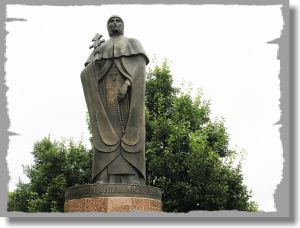 Выполненный в виде скульптуры в полный рост. В правой приподнятой руке держит крест, в левой руке чётки. Одета в монашеское облачение.