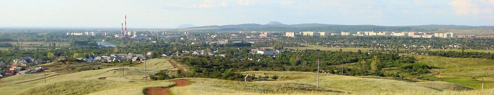 Панорама города Ишимбая: слева направо — микрорайон Перегонный, река Белая, Ишимбайская ГТУ, центральная часть города. На горизонте — шиханы Куштау и Тратау