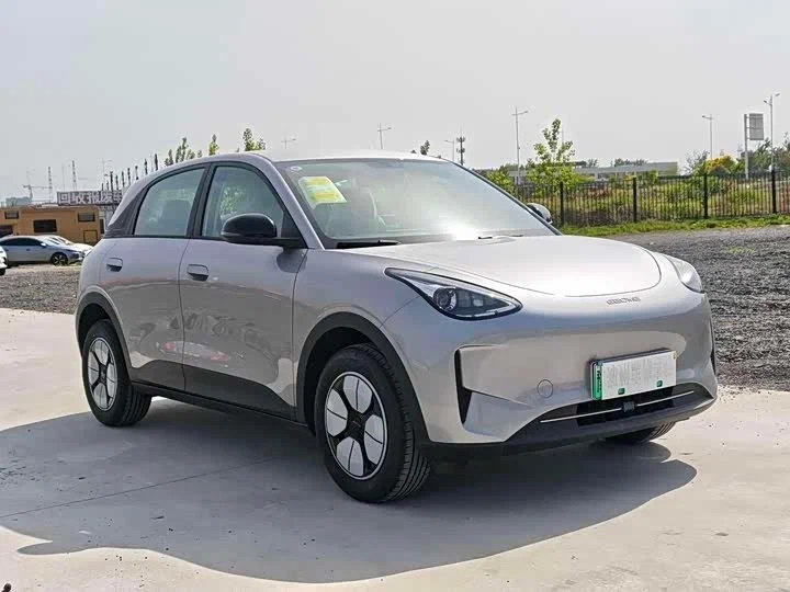 Geely Galaxy Xingyuan (карточка geely-galaxy-xingyuan-2026) — вид спереди три четверти, компактный электрохэтчбек на фоне открытой площадки в Китае перед отправкой.