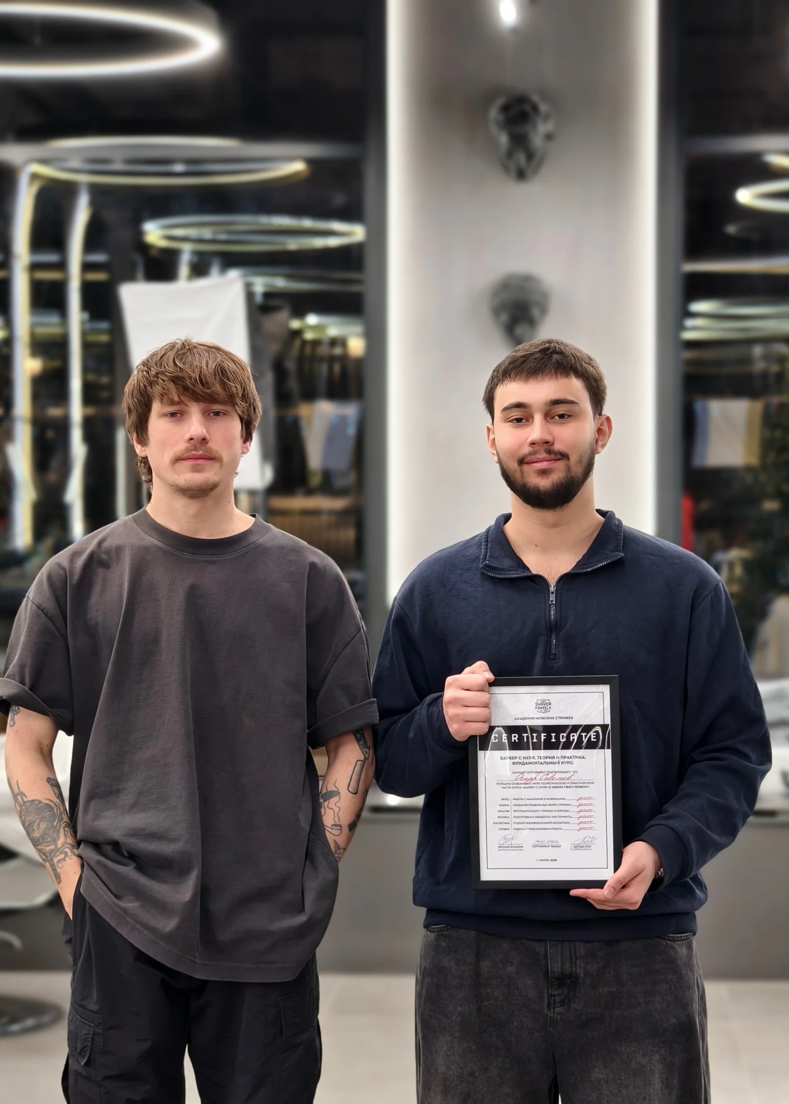 Выпускник с сертификатом рядом с преподавателем академии