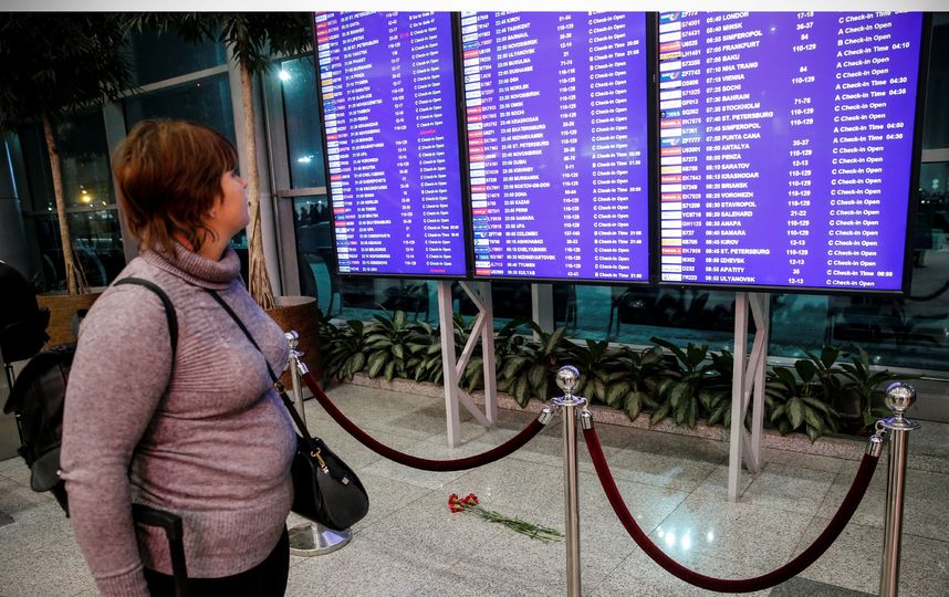 Люди оставляют цветы под расписанием полётов в столичном аэропорту Домодедово. Фото AFP