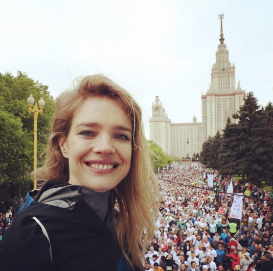 Организатор забега "Бегущий сердца" Наталья Водянова на фоне спортсменов и здания МГУ в Москве. Фото instagram/natasupernova