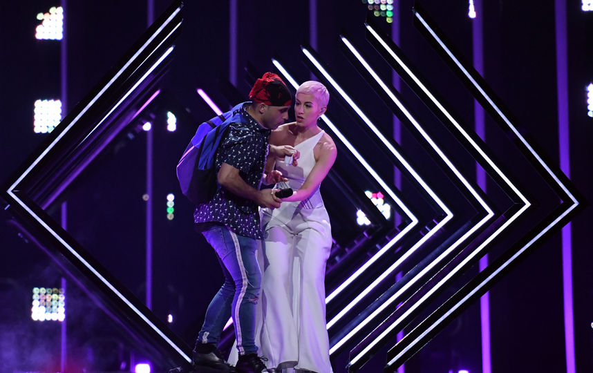 неизвестный мужчина решил добавить эпатажа номеру британской певицы SuRie. Он выбежал из зрительского зала, силой забрал у неё микрофон и попытался начать петь. Фото AFP