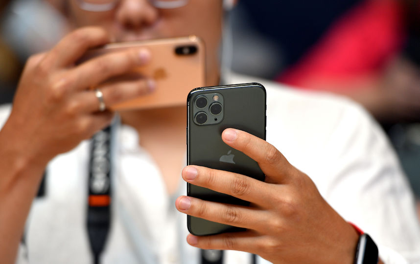 Люди с выставочными смартфонами на презентации. Фото AFP