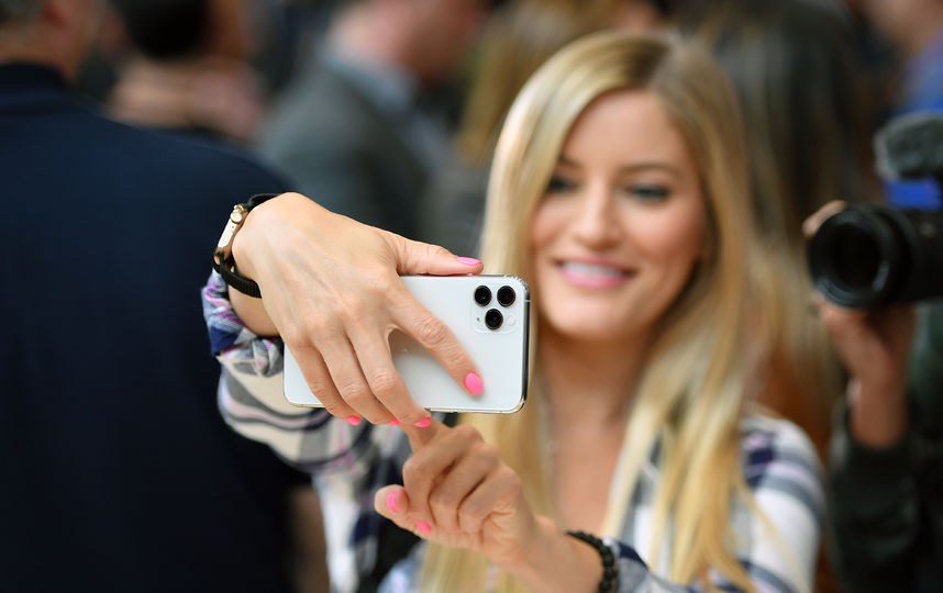 Люди с выставочными смартфонами на презентации. Фото AFP