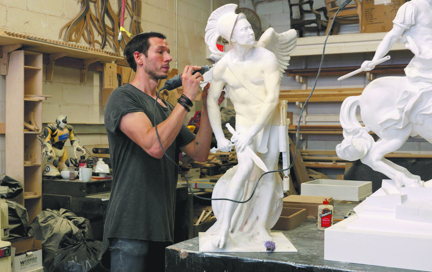скульптор работает над мраморной статуей в мастерской