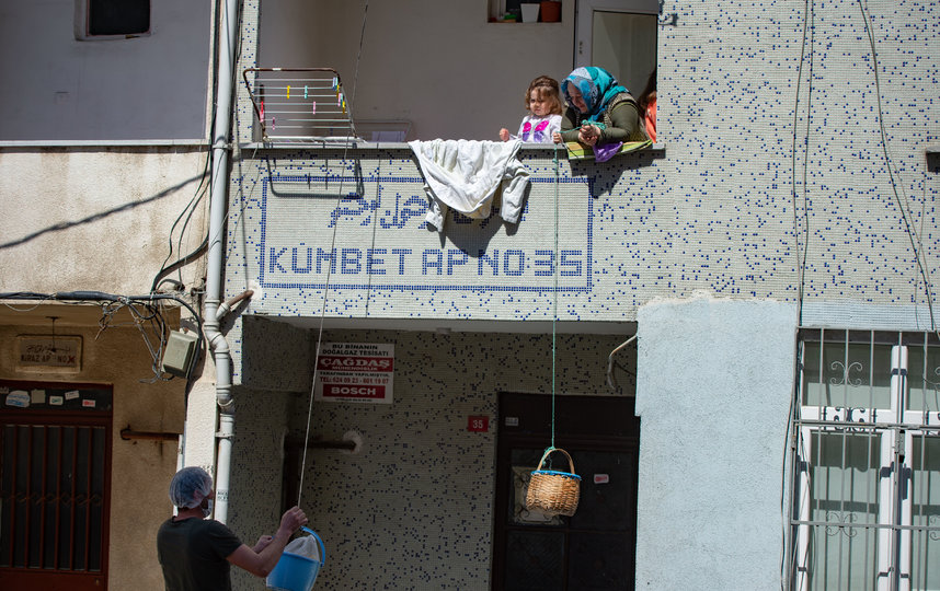 Получают продукты: Пекарь кладет хлеб в корзину, спущенную женщиной с ее балкона. Стамбул, Турция. Фото AFP