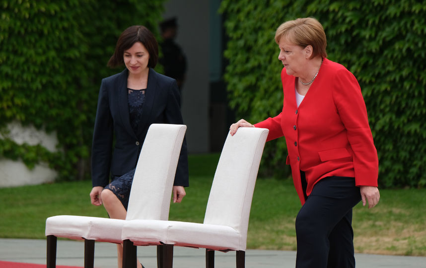 Меркель и премьер-министр Молдавии Майя Санду прослушали гимны двух стран сидя на стульях с белой тканью. Фото Getty