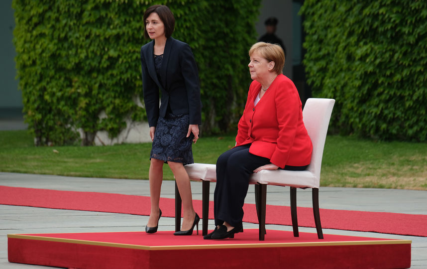 Меркель и премьер-министр Молдавии Майя Санду прослушали гимны двух стран сидя на стульях с белой тканью. Фото Getty