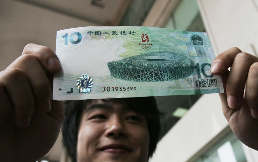 Мужчина с купюрой достоинством десять юаней. Фото Getty