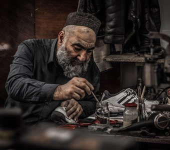 Работающий в обувной мастерской старик