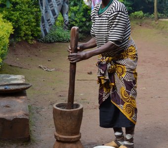 Африканская женщина в ступе перемалывает кофейные зерна.