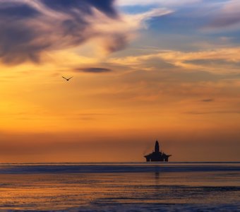 Нефтянная буровая платформа на закате.