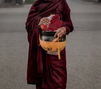 Бирманский монах с чашами для утреннего подношения еды