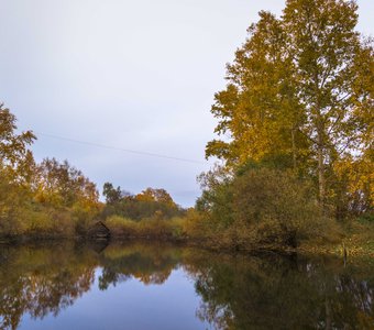 Старый сарай на реке в осеннем лесу.