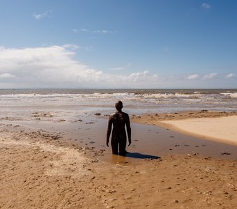 Прилив накрывает статую на пляже Crosby Beach