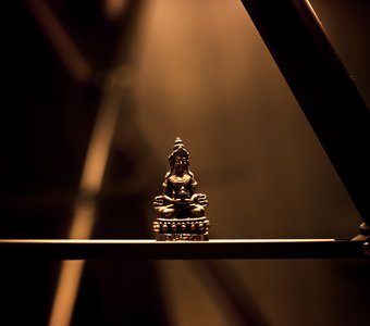 Сидящий Будда на штативе от фотоаппарата.