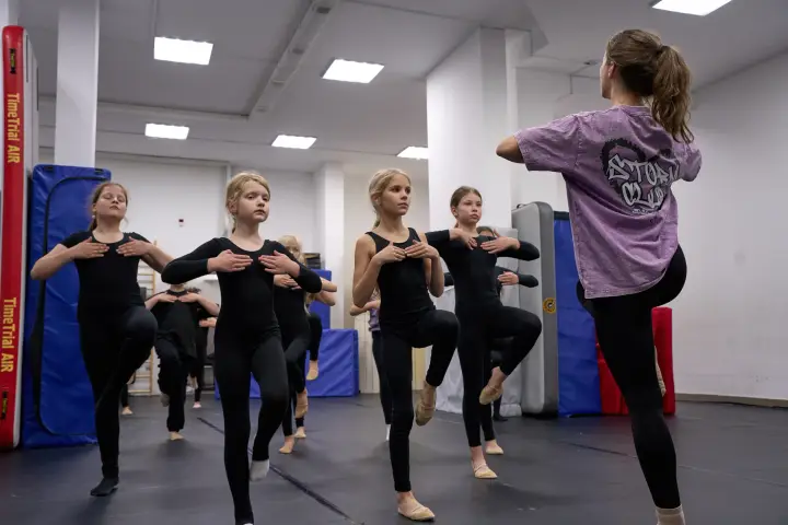 Тренер и спортсменки выполняют упражнение с подъёмом колена