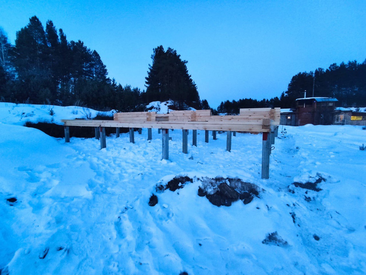 Сборка деревянного ростверка на оголовках железобетонных свай — основание под дом на зимнем лесном участке