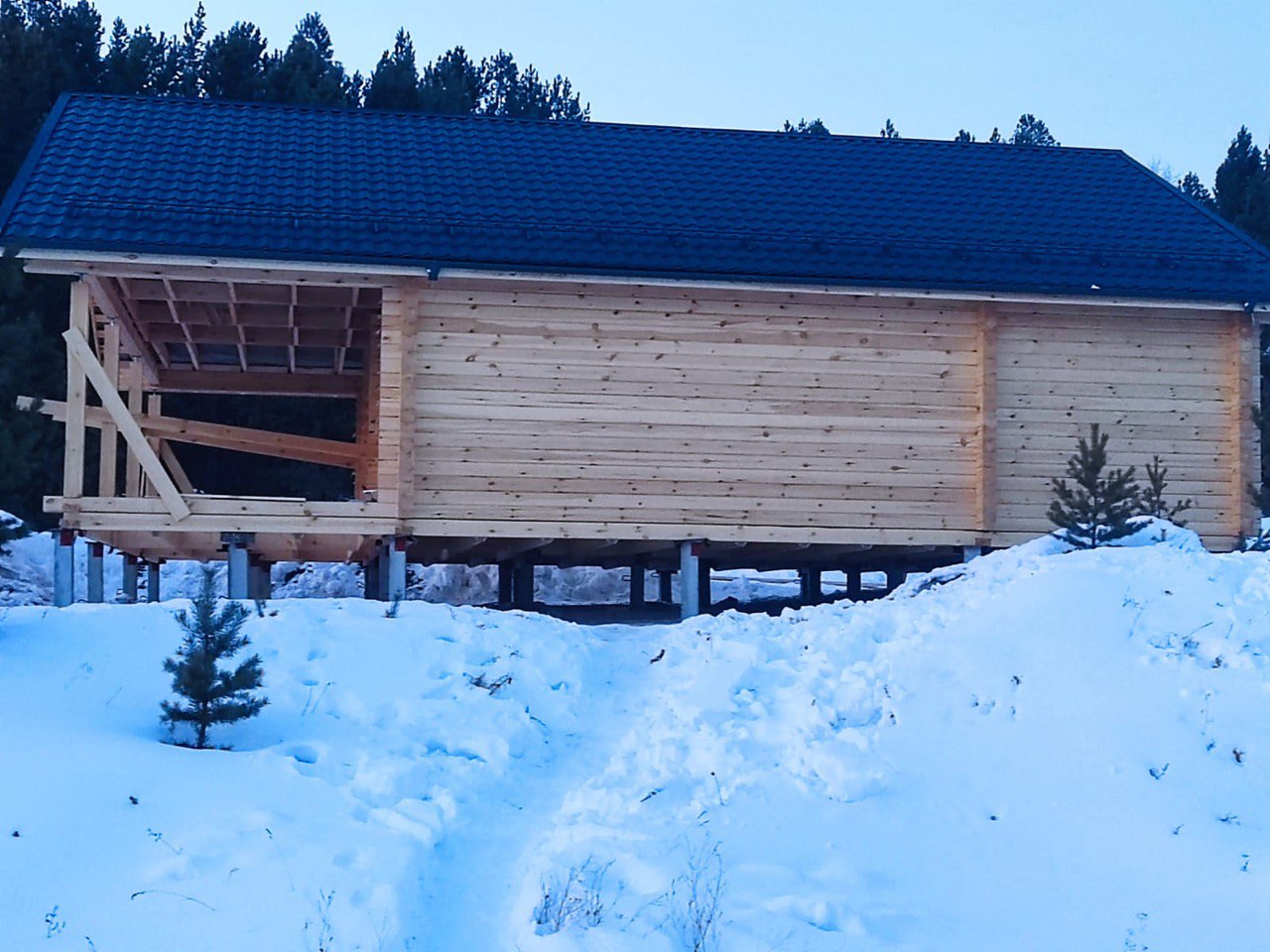 Дом из бруса на фундаменте из железобетонных свай — боковой вид, сборка веранды, крыша из металлочерепицы, зимнее строительство