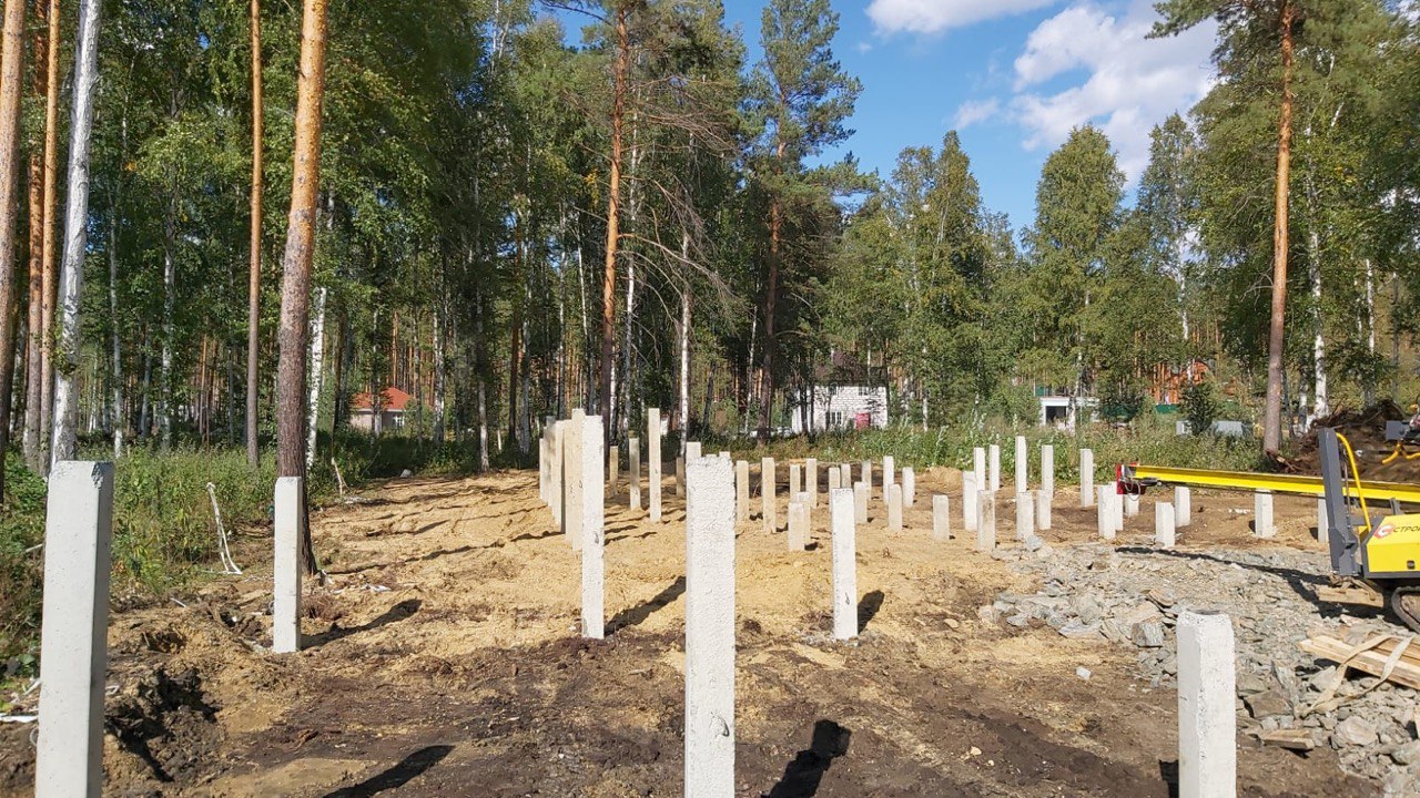 Общий вид свайного поля в сосново‑берёзовом лесу, выровненная песчаная подготовка и ряды забитых свай