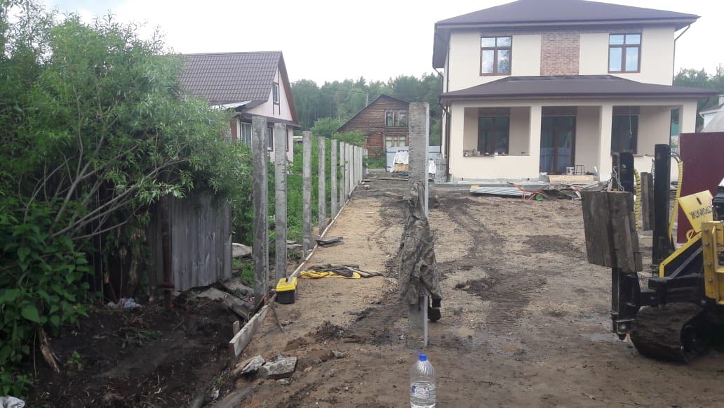 Участок перед домом с установленными бетонными стойками под ограждение; подготовка основания, рядом стопка блоков и доски (Нижний Тагил, Черемушки)