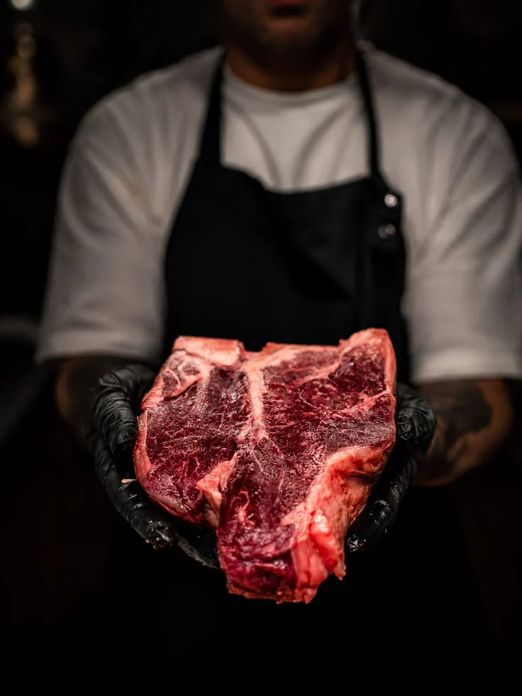Мясник держит стейк T-bone