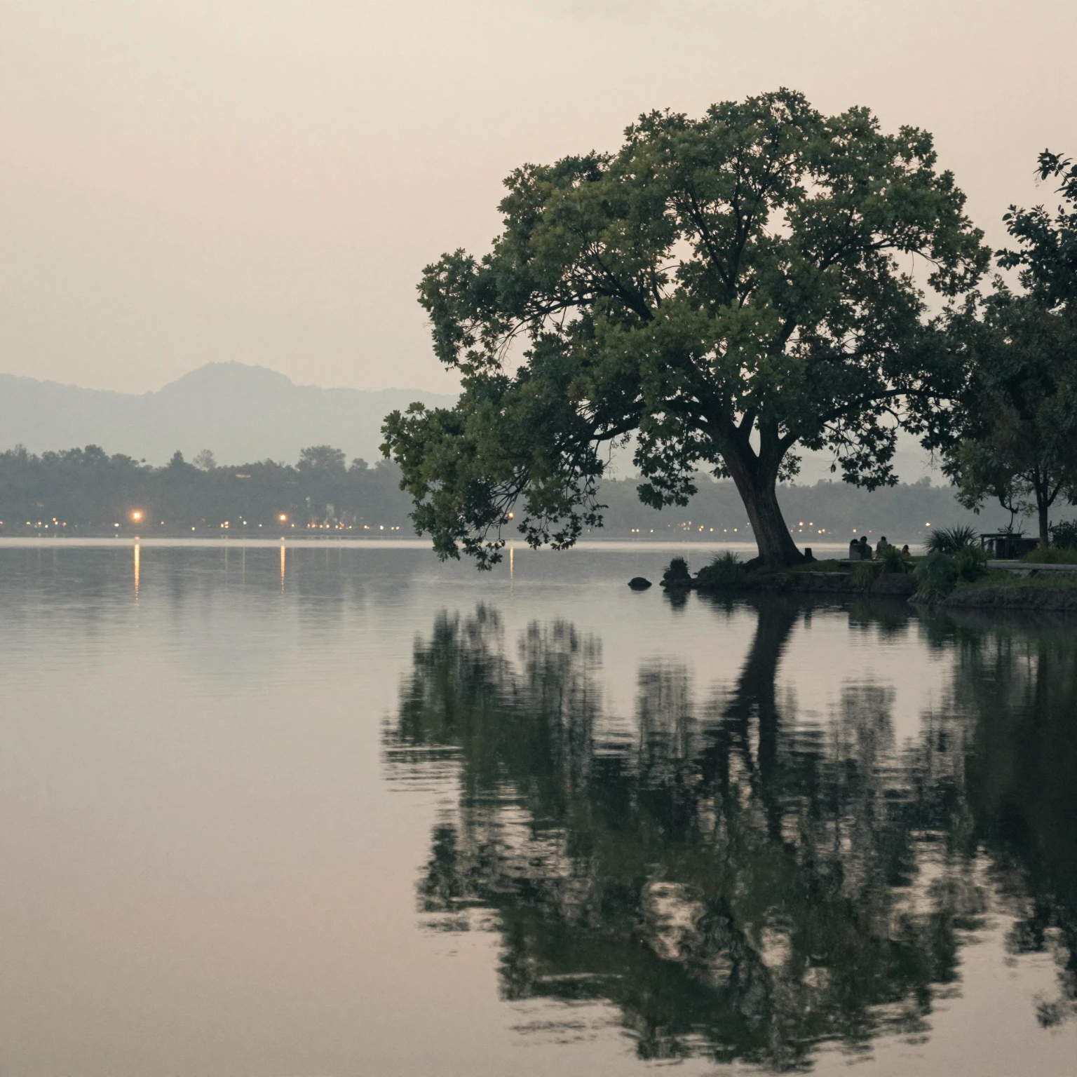 A tranquil lake reflecting the soft glow of distant lights a...